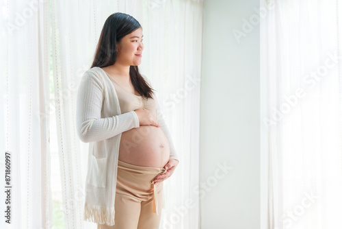 An Asian young pregnant wife relaxes at home, her hand gently resting on her belly, filled with love and anticipation as she embraces the journey of impending motherhood. Free Download An Asian young pregnant wife relaxes at home, her hand gently resting on her belly, filled with love and anticipation as she embraces the journey of impending motherhood. - GFXLoad