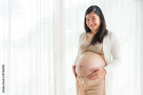 An Asian young pregnant wife relaxes at home, her hand gently resting on her belly, filled with love and anticipation as she embraces the journey of impending motherhood. Free Download An Asian young pregnant wife relaxes at home, her hand gently resting on her belly, filled with love and anticipation as she embraces the journey of impending motherhood. - GFXLoad