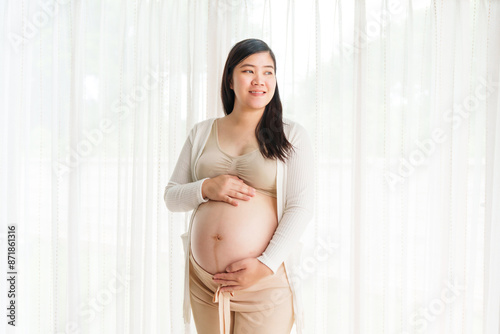 An Asian young pregnant wife relaxes at home, her hand gently resting on her belly, filled with love and anticipation as she embraces the journey of impending motherhood. Free Download An Asian young pregnant wife relaxes at home, her hand gently resting on her belly, filled with love and anticipation as she embraces the journey of impending motherhood. - GFXLoad