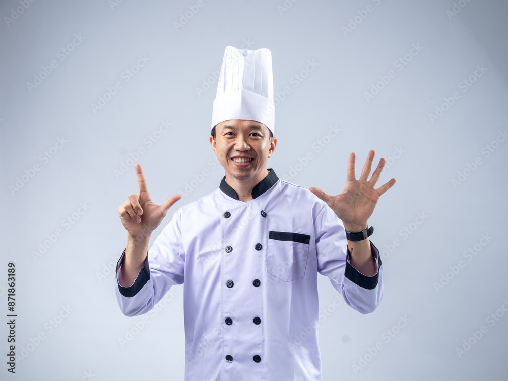 A smiling Asian male chef in a white uniform and hat holds up seven fingers, signifying the number seven, against a light blue background. The setting is professional and engaging A smiling Asian male chef in a white uniform and hat holds up seven fingers, signifying the number seven, against a light blue background. The setting is professional and engaging