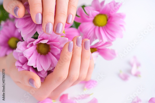 Hands of a woman with pink manicure on nails and pink flowers