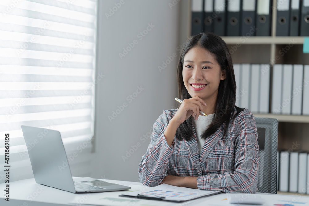 Sharing good business news. Attractive young businesswoman talking on the mobile phone and smiling while sitting at her working place in office and looking at laptop PC. Sharing good business news. Attractive young businesswoman talking on the mobile phone and smiling while sitting at her working place in office and looking at laptop PC.