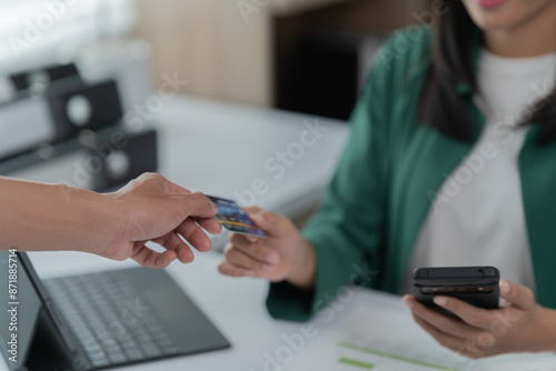 mage of a young Asian businesswoman holding a credit card.