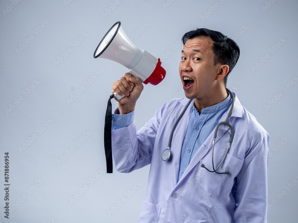 Asian male doctor in a white coat holding a megaphone and speaking enthusiastically. The plain background emphasizes the focus on the doctor's energetic announcement and the stethoscope Asian male doctor in a white coat holding a megaphone and speaking enthusiastically. The plain background emphasizes the focus on the doctor's energetic announcement and the stethoscope