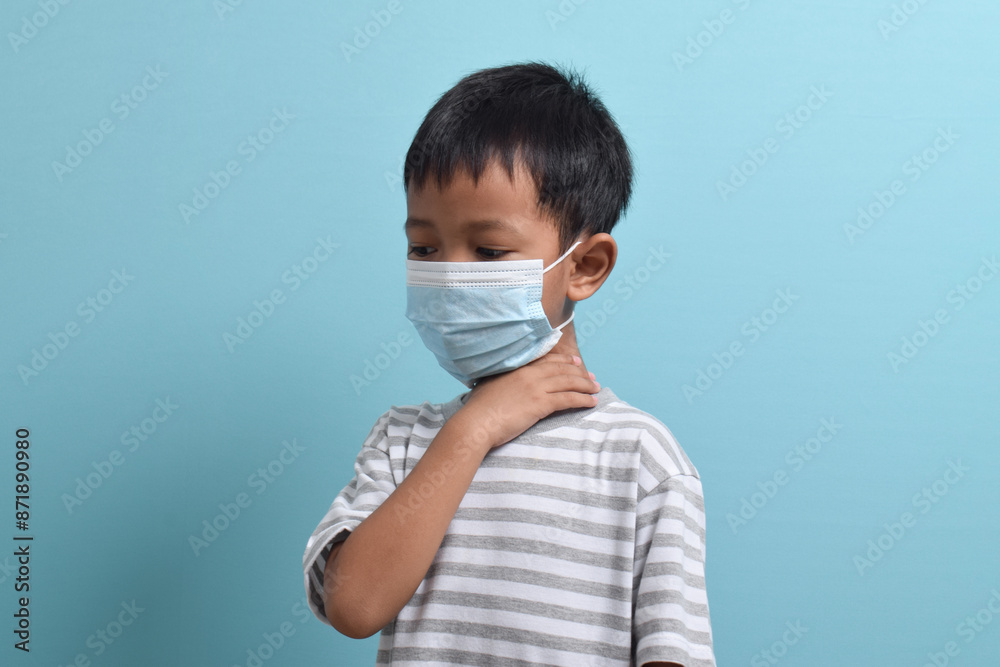 Asian Boy wearing health mask isolated on blue background. Medical and health concept. Human population viruses, infections, flu disease prevention Asian Boy wearing health mask isolated on blue background. Medical and health concept. Human population viruses, infections, flu disease prevention