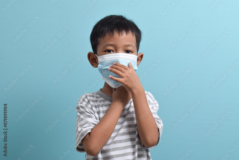 Asian Boy wearing health mask isolated on blue background. Medical and health concept. Human population viruses, infections, flu disease prevention Asian Boy wearing health mask isolated on blue background. Medical and health concept. Human population viruses, infections, flu disease prevention