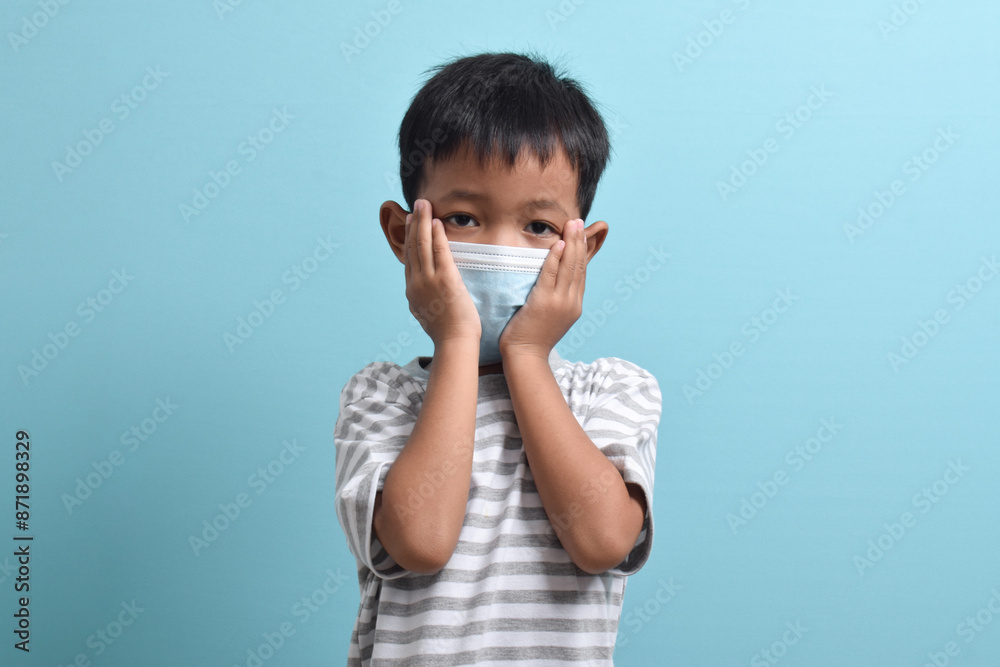 Asian Boy wearing health mask isolated on blue background. Medical and health concept. Human population viruses, infections, flu disease prevention