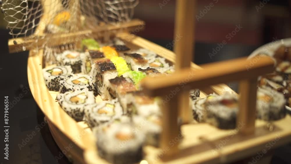 toma desde arriba de un grupo de rolls de sushi en una mesa de comida japonesa dentro de un barquito de madera