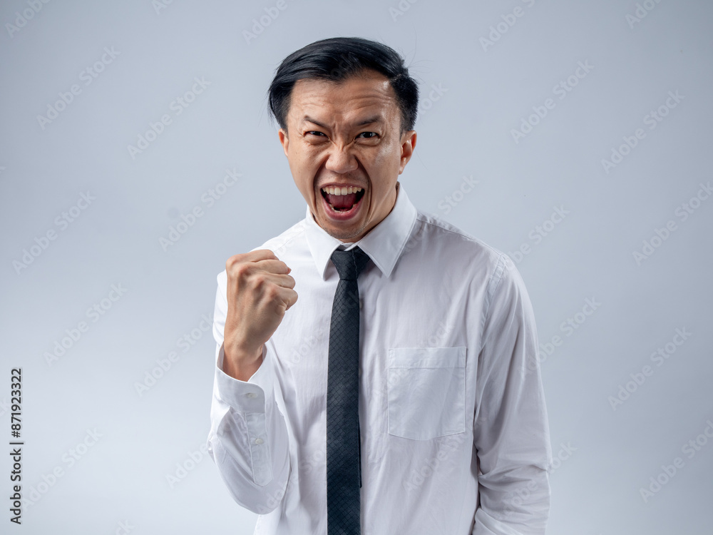 Asian businessman in white shirt and black tie celebrating success with fists clenched and mouth open in excitement, standing against a plain light background. His joyful expression and victory pose Asian businessman in white shirt and black tie celebrating success with fists clenched and mouth open in excitement, standing against a plain light background. His joyful expression and victory pose