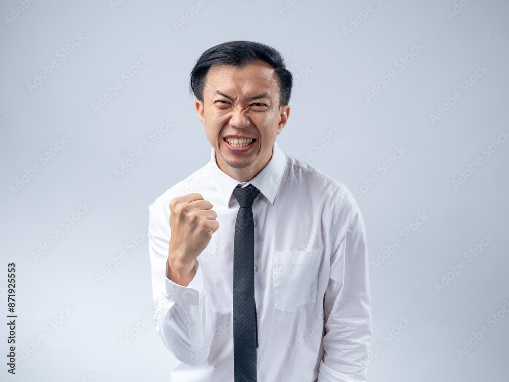 Asian businessman in white shirt and black tie celebrating success with fists clenched and mouth open in excitement, standing against a plain light background. His joyful expression and victory pose Asian businessman in white shirt and black tie celebrating success with fists clenched and mouth open in excitement, standing against a plain light background. His joyful expression and victory pose