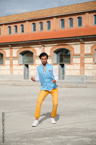 Obraz na płótnie Stylish man is celebrating in the street by dancing in front of a brick building w salonie