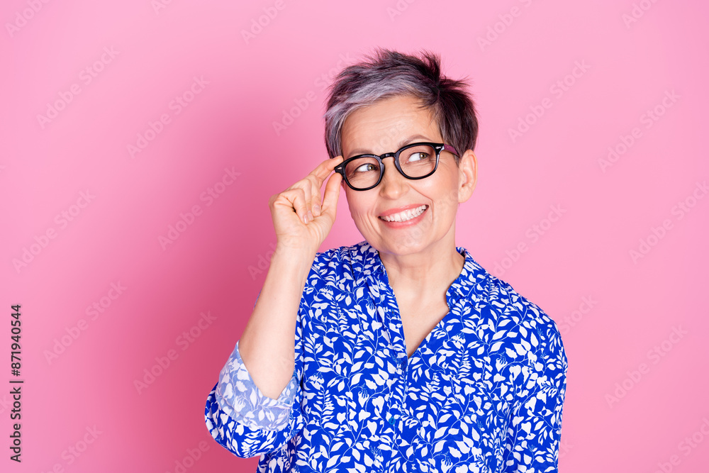 Photo of good mood senior person with gray hair dressed print blouse touching glasses look empty space isolated on pink color background