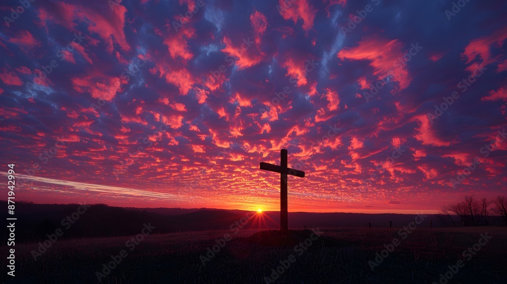 Obraz premium A cross silhouetted against the sky at sunset, with vibrant red and purple clouds creating an epic backdrop. The scene captures the power of God's love in its most majestic.