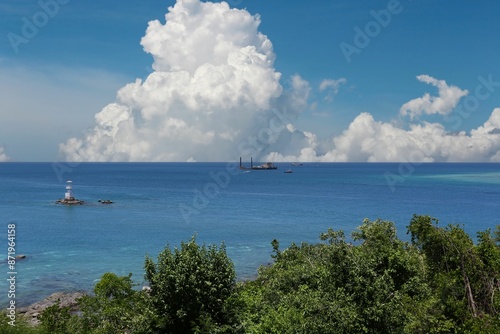 Blue sea with boats floating on the surface on a clear day.