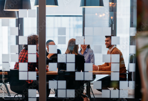 In a sleek glass office space, a team of business professionals engage in lively discussions and exchange strategic ideas, showcasing collaboration and innovation at the heart of modern corporate photo