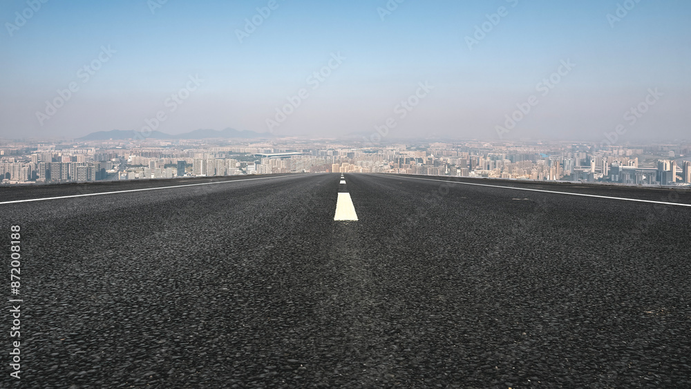 Fototapeta premium Endless Asphalt Road Leading to Urban Skyline