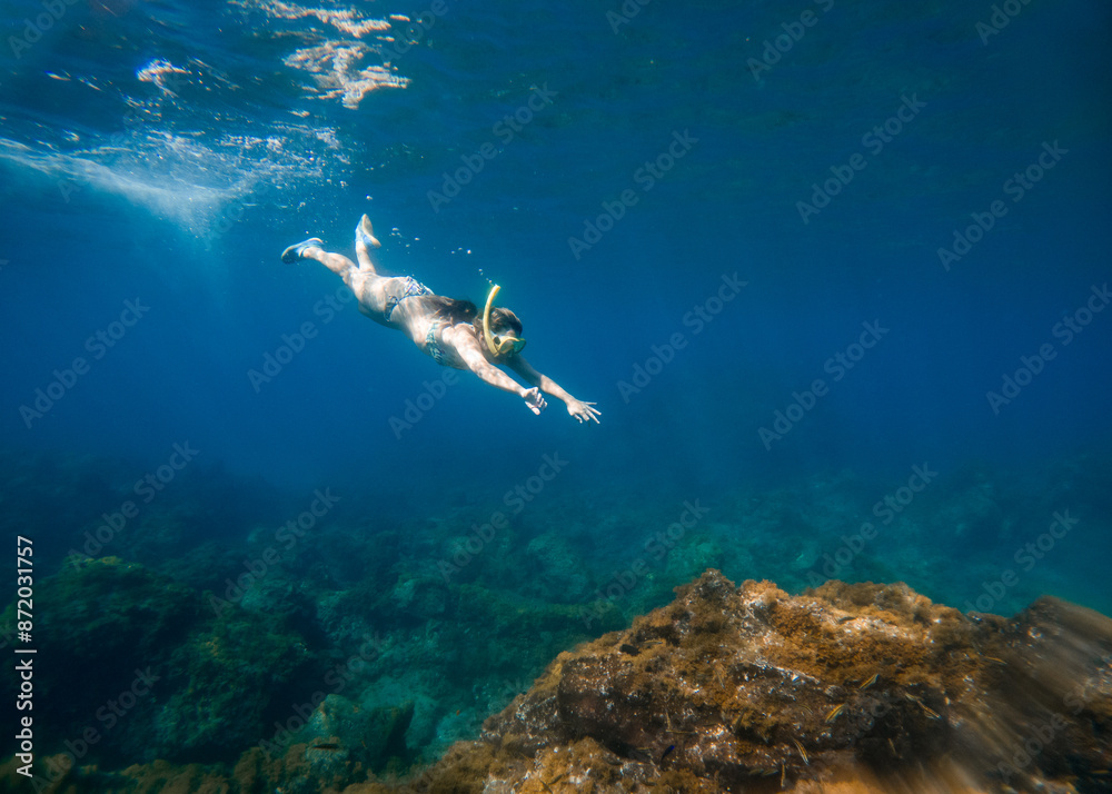 Fototapeta premium Woman snorkeling under water in a turquoise sea