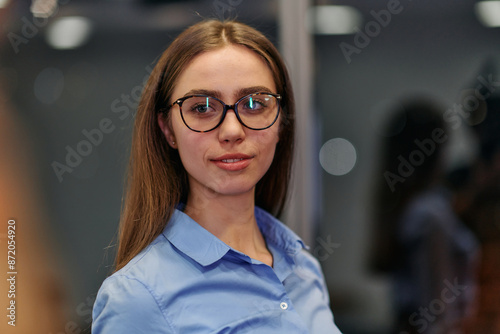 Confident Businesswoman in Glasses and Blue Shirt Engaged in Office Discussion