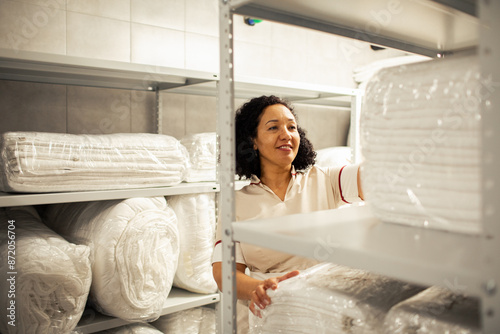 Woman maid organizing linens in a hotel storage room