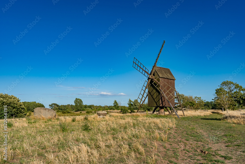 Naklejka premium Beautiful windmill. Countryside landscape with old traditional wooden windmill in rural area of southern Sweden.