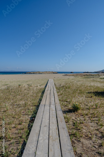 View of a wooden path leading to the beautiful sandy beach of Magganari in Ios Greece photo