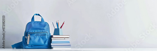 Back to school concept with backpack and books on solid color background, copy space for text