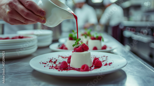 a chef drizzling a vibrant raspberry coulis over a plate of beautifully plated panna cotta, with a blurred kitchen background