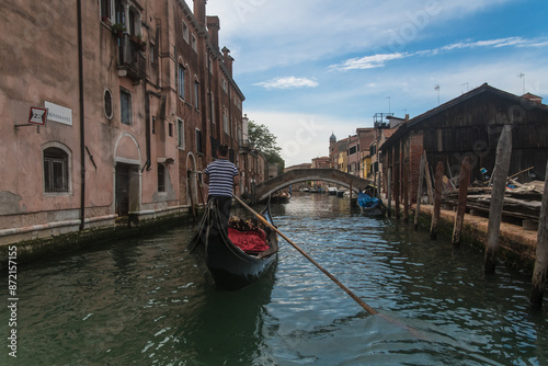 Un gondoliere rema in un canale di Venezia in una giornata nuvolosa di primavera