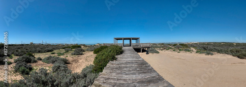 Panoramic view with a wooden path leading to a viewpoint located in the Torunos Natural Park, in El Puerto de Santa María, with Cadiz in the background. photo