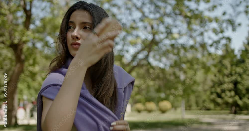 A beautiful young woman in a park brushes her hair, enjoying the sunny day. She looks serene and relaxed, surrounded by lush greenery. A beautiful young woman in a park brushes her hair, enjoying the sunny day. She looks serene and relaxed, surrounded by lush greenery.