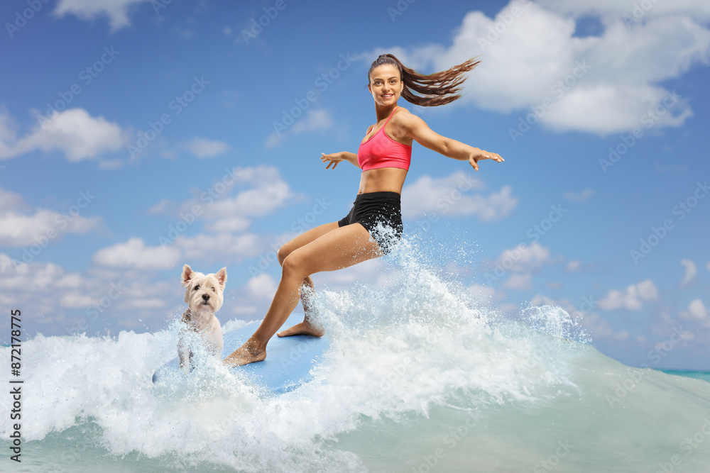 Naklejka premium Female surfer with a dog riding a surfboard on a wave