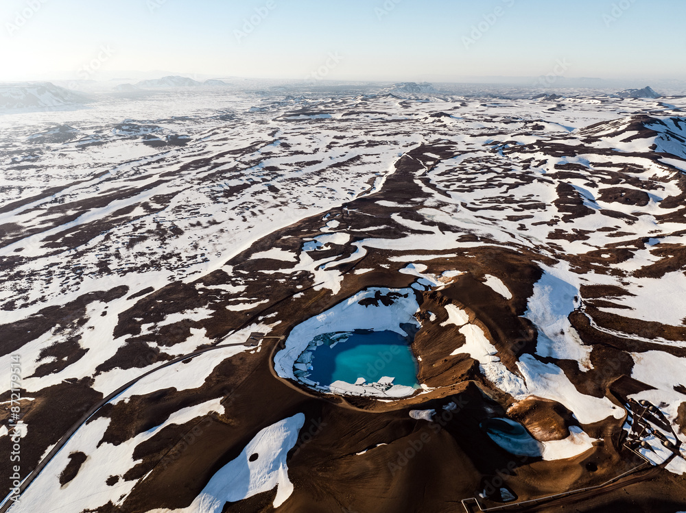 View from above, stunning aerial view of the Krafla Viti crater. This beautiful Crater is filled with blue water and surrounded by a geothermal area and colorful mountains. Iceland.
