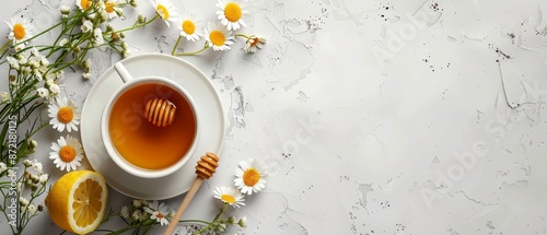  A cup of tea with honey on a saucer Surrounded by daisies Honey dip with wooden spoon nearby