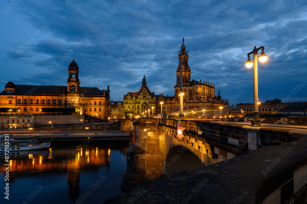 Fototapeta premium Night shot of the brightly lit skyline of the historic old town of Dresden with the River Elbe in the foreground.