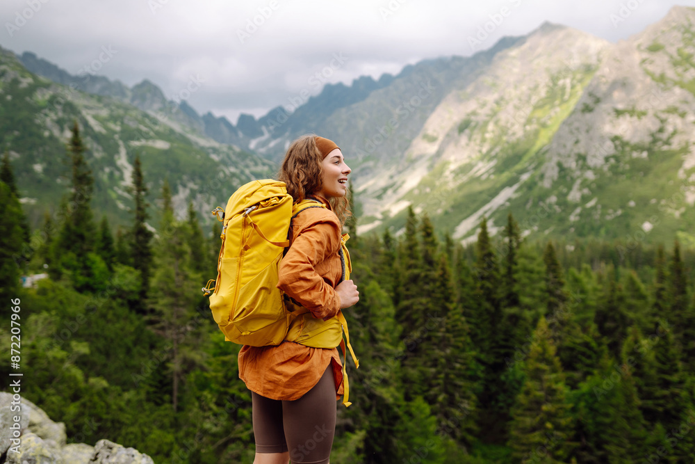 Active woman tourist with backpack enjoys the beautiful scenery of the majestic mountains. Travel, adventure. Concept of an active lifestyle.