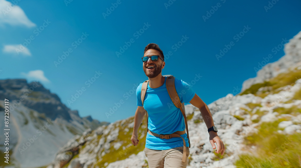 An ecstatic man in a bright blue T-shirt and beige shorts climbing a summer mountain trail An ecstatic man in a bright blue T-shirt and beige shorts climbing a summer mountain trail