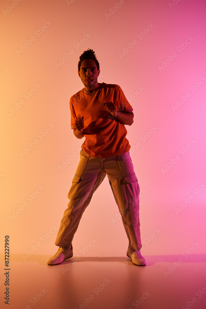 A young African American man dances against a vibrant gradient background. A young African American man dances against a vibrant gradient background.
