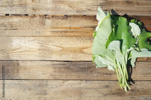 Bunch of fresh burdock leaves on a wooden surface