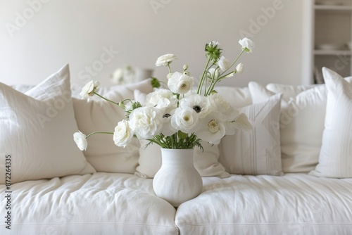 Bouquet of white flowers in a vase on a white sofa.