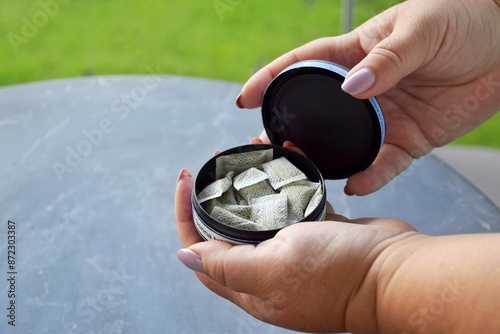 Open Box of snus pads in female hands. photo