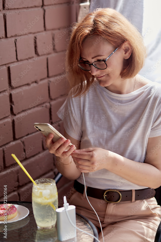 Energized efficiency a remote worker ensures her devices are powered with a portable charger Energized efficiency a remote worker ensures her devices are powered with a portable charger