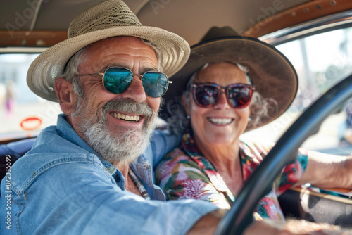 Travel, companionship, and living life to the fullest in their golden years during trip. Happy elderly senior couple enjoying a road trip in a vintage car, both wearing sunglasses and smiling © Valeriia
