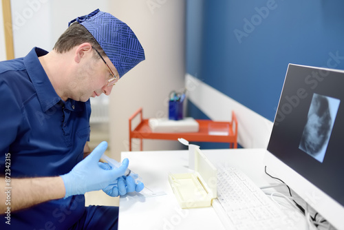 Oncologist performing a cancer biopsy test during the appointment of patient. The doctor applies a sample from a syringe to a slide. photo