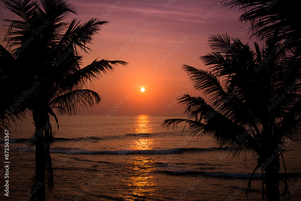 A tranquil tropical sunset with palm trees and colorful sky over ocean waves is a peaceful view perfect for relaxation A tranquil tropical sunset with palm trees and colorful sky over ocean waves is a peaceful view perfect for relaxation