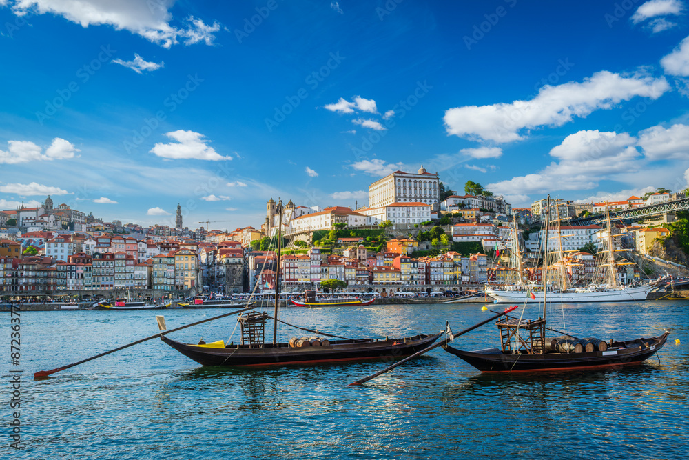 Fototapeta premium View of Porto city and Douro river with traditional boats with port wine barrels and sailing ship from famous tourist viewpoint Marginal de Gaia riverfront. Porto, Vila Nova de Gaia, Portugal