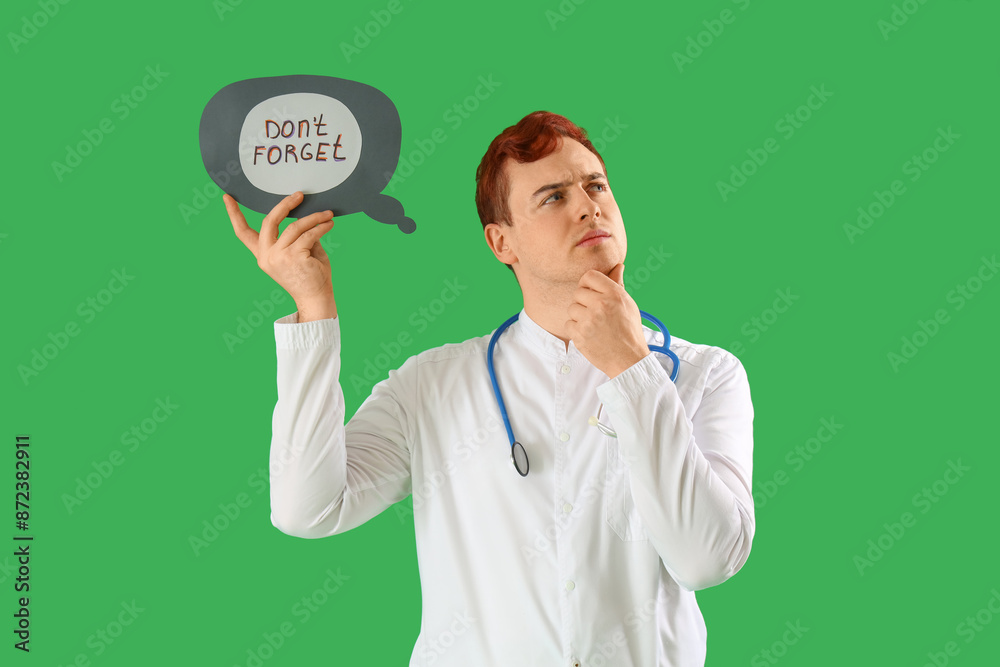 Thoughtful doctor holding speech bubble with text DON'T FORGET on green background Thoughtful doctor holding speech bubble with text DON'T FORGET on green background