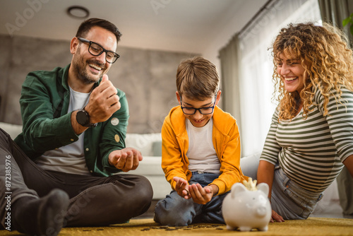 mam dad and son sit on the carpet and save money in the piggy bank