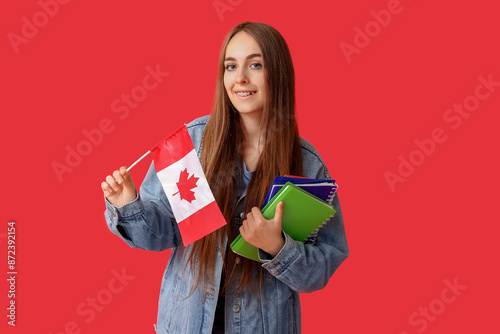 Female student with notebooks and flag of Canada on red background