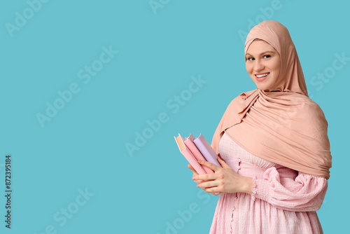 Photography Beautiful young happy Muslim woman with books on blue background