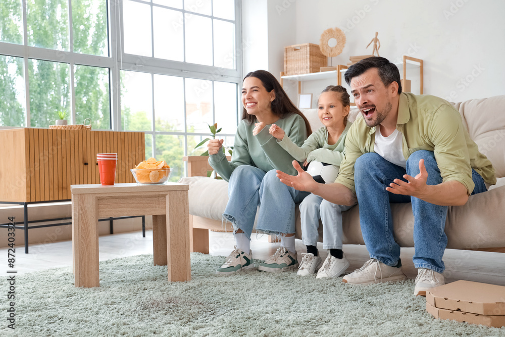 © Pixel-Shot - Happy family with soccer ball cheering for football team at home